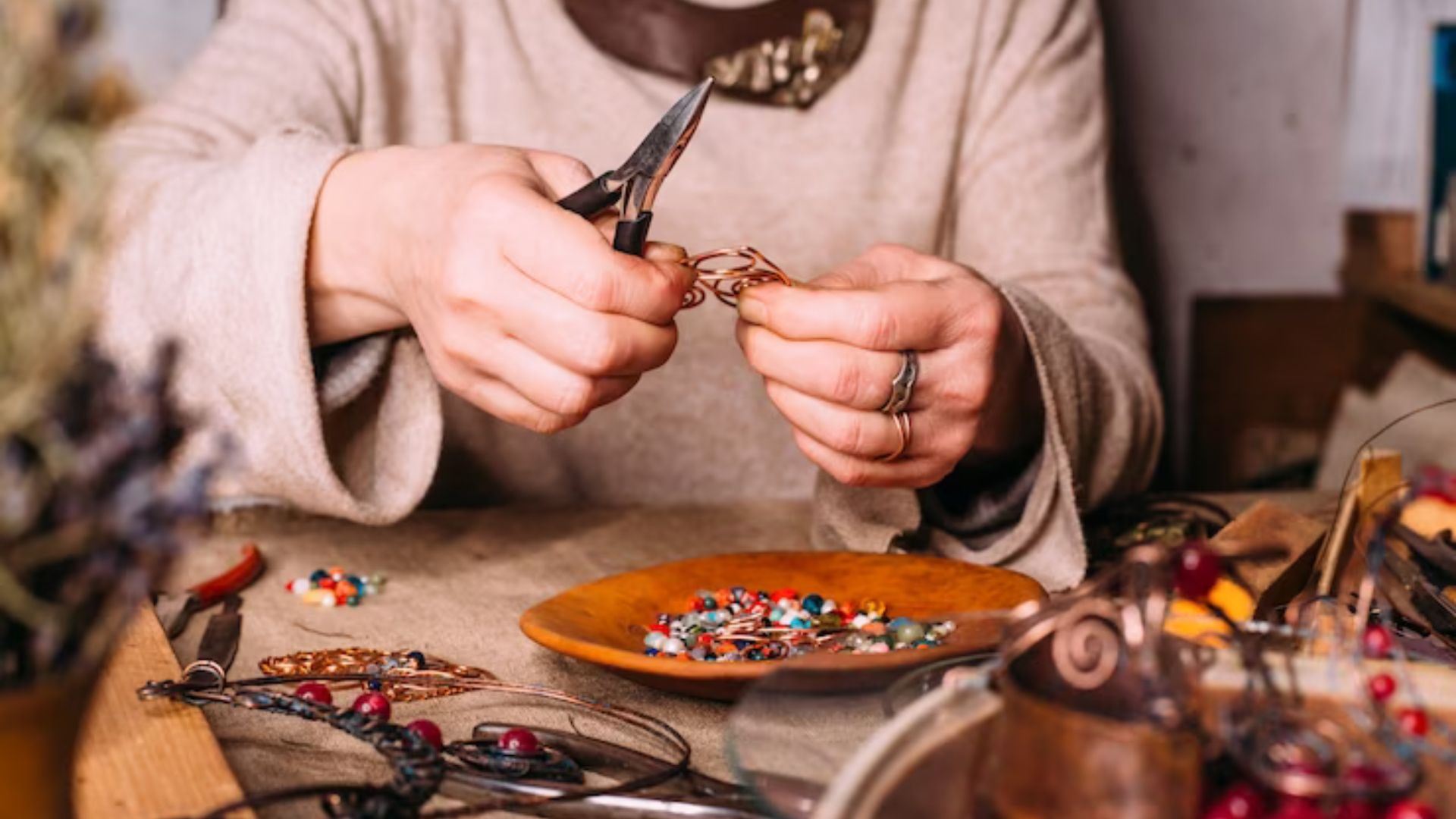 A woman making pieces of jewelry using clay beads.