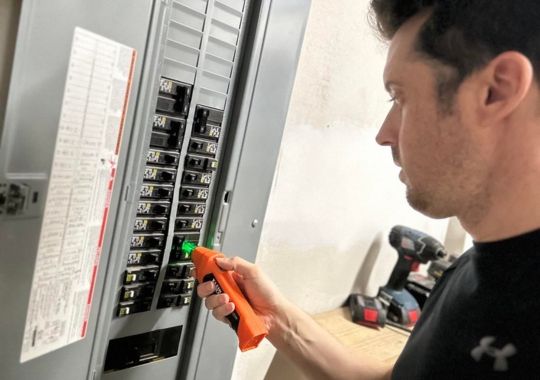 A man looking for circuit breakers using the klein ET310.