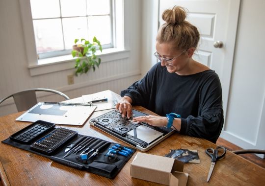 A female technician working on the laptop using the ifixit tools.